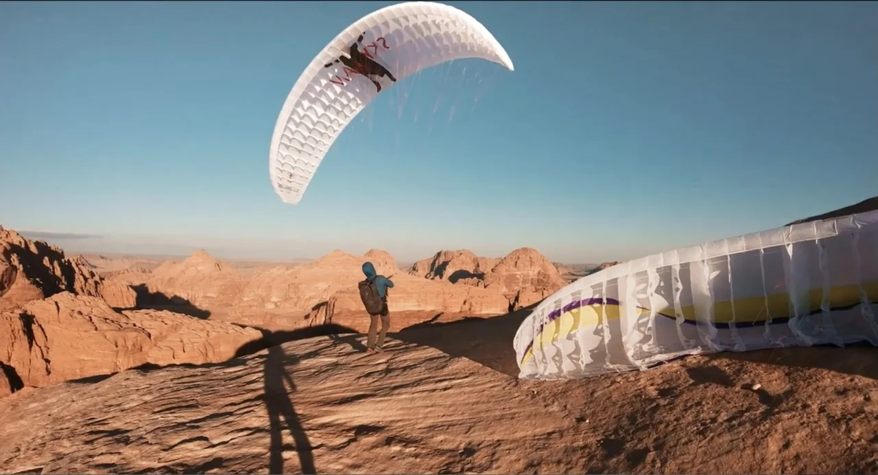 Crooked Trees Gon Give Me Wings (2022) movie still: wide — A rugged desert cliff overlooks a vast landscape of arid rock formations under a clear…
