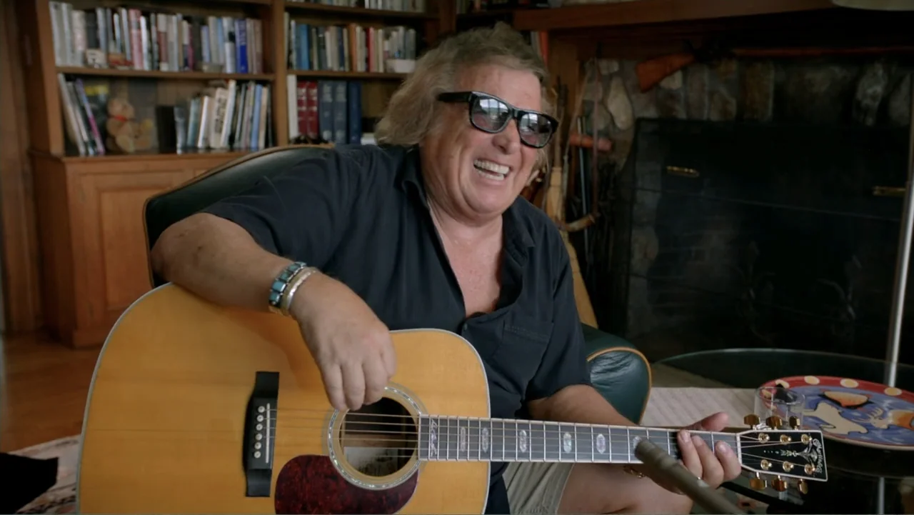 The Day the Music Died: The Story of Don McLean's "American Pie" (2022) movie still: medium — A man sits in a leather chair in a room with built-in…