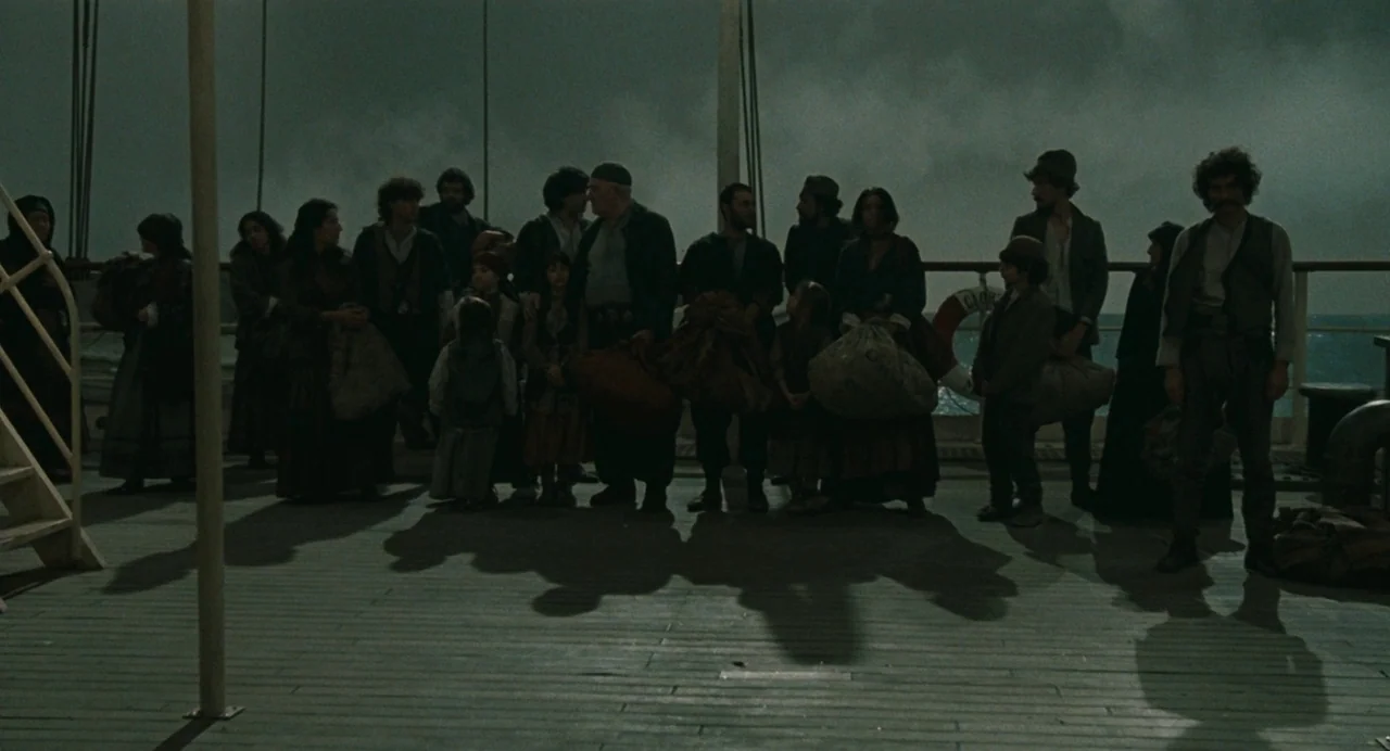 And The Ship Sails On (1983) movie still: fullbody — A group of people stands together on the wooden deck of a large ship. The sky above is cloudy…