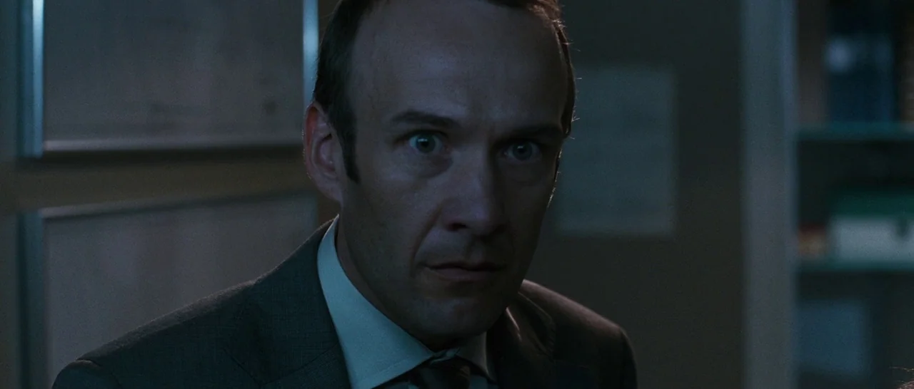 Sound of Noise (2010) movie still: closeup — A dimly lit storage area features shelves with medical supplies in the background. A man stands in the…