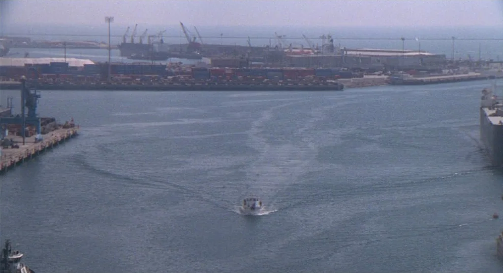The Crossing Guard (1995) movie still: establishing — A wide industrial harbor view with large shipping cranes and stacked containers in back. A…