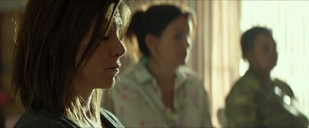 Cake (2014) movie still: medium — Three women sit indoors in a room with light-colored curtains covering a window. The woman in the foreground has…