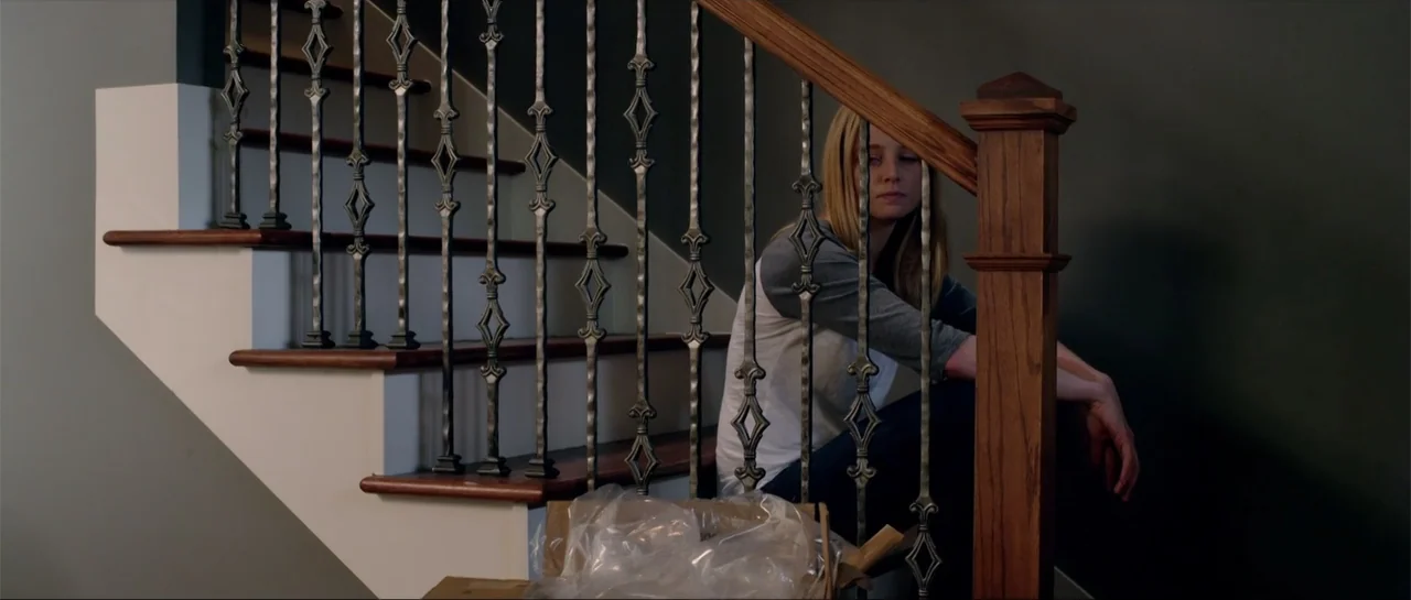 Rage (2014) movie still: medium — A residential staircase features a dark-stained wood handrail and ornate decorative iron balusters. A young woman…