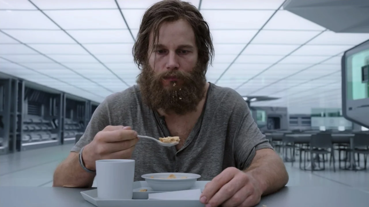 Passengers (2016) movie still: medium — A minimalist, sterile cafeteria with futuristic white paneling and rows of metal tables. A bearded man sits…