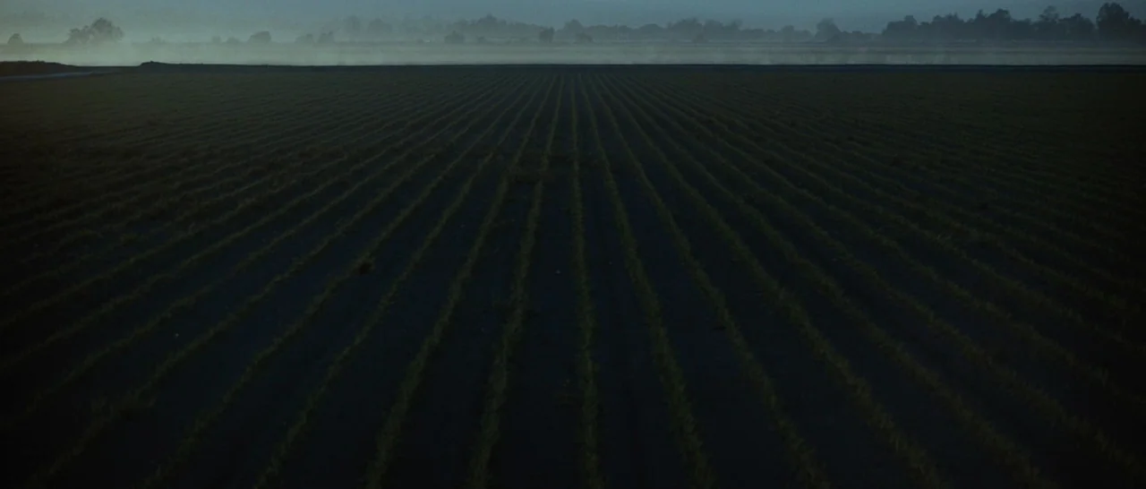 Star Trek (2009) movie still: establishing — A vast, plowed field stretches to the horizon under a pale, misty dawn sky. Thin, parallel rows of…