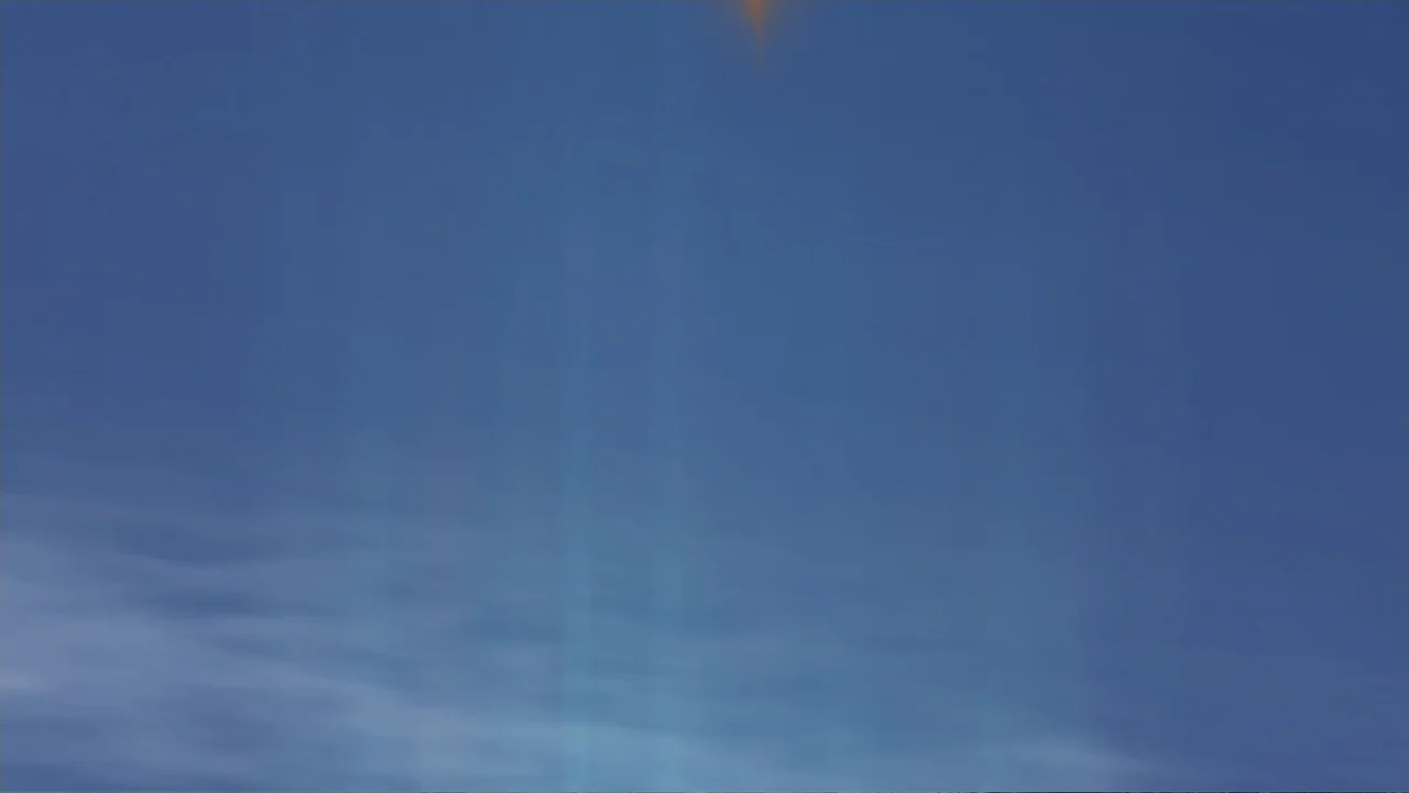 Reign of the Supermen (2019) movie still: establishing — A clear blue sky fills the frame with light wispy clouds at the bottom. A faint orange lens…