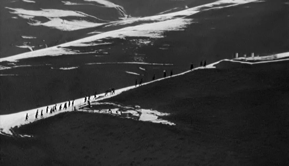 The Plea (1968) movie still: establishing — A vast, high-altitude landscape is dominated by dark, rugged mountain slopes covered with snow. A long…