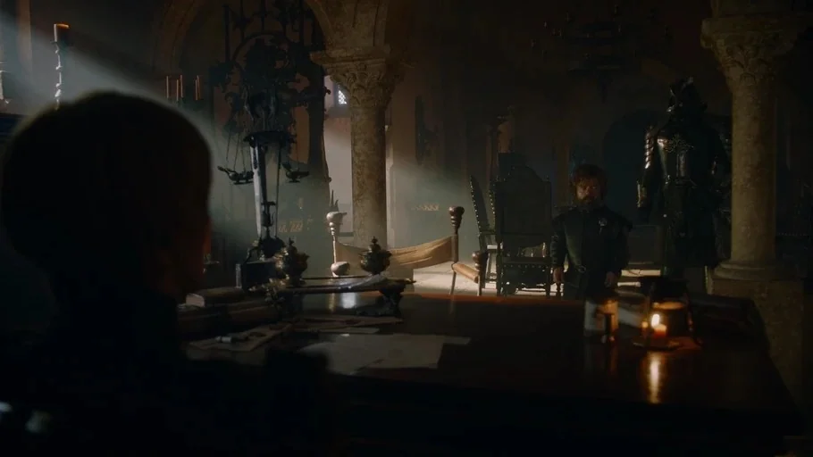 Game of Thrones (2017) movie still: wide — A dark stone hall with columns features an ornate chair and a desk. A man stands in the distance while…