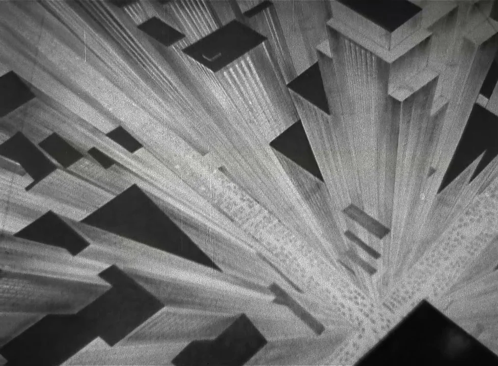 Swing Time (1936) movie still: establishing — A stylized top-down perspective of a dense urban intersection with towering geometric skyscrapers.…