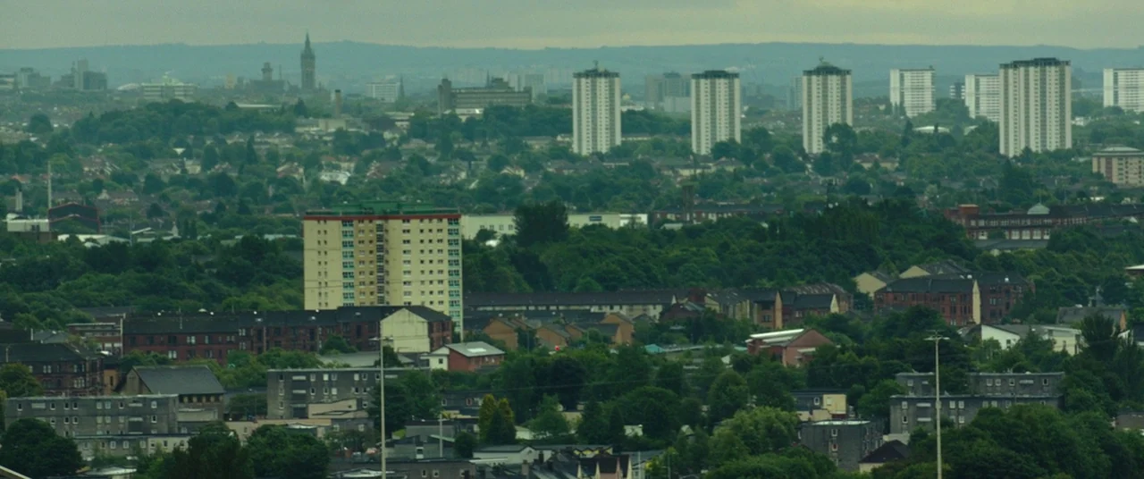 Wild Rose (2018) movie still: establishing — An aerial view of a dense residential area featuring several high-rise tower blocks. Lush green trees…