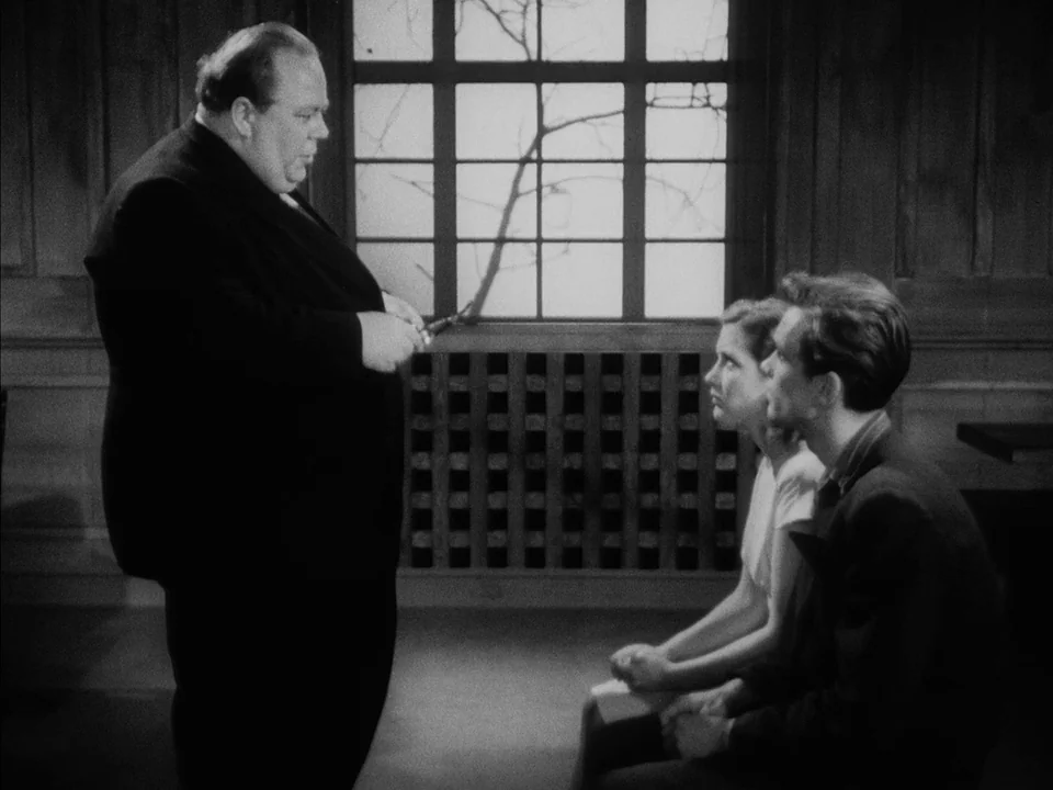It Rains On Our Love (1946) movie still: medium — A dark, wood-paneled room features a large window with a branch visible outside. A heavy-set man…