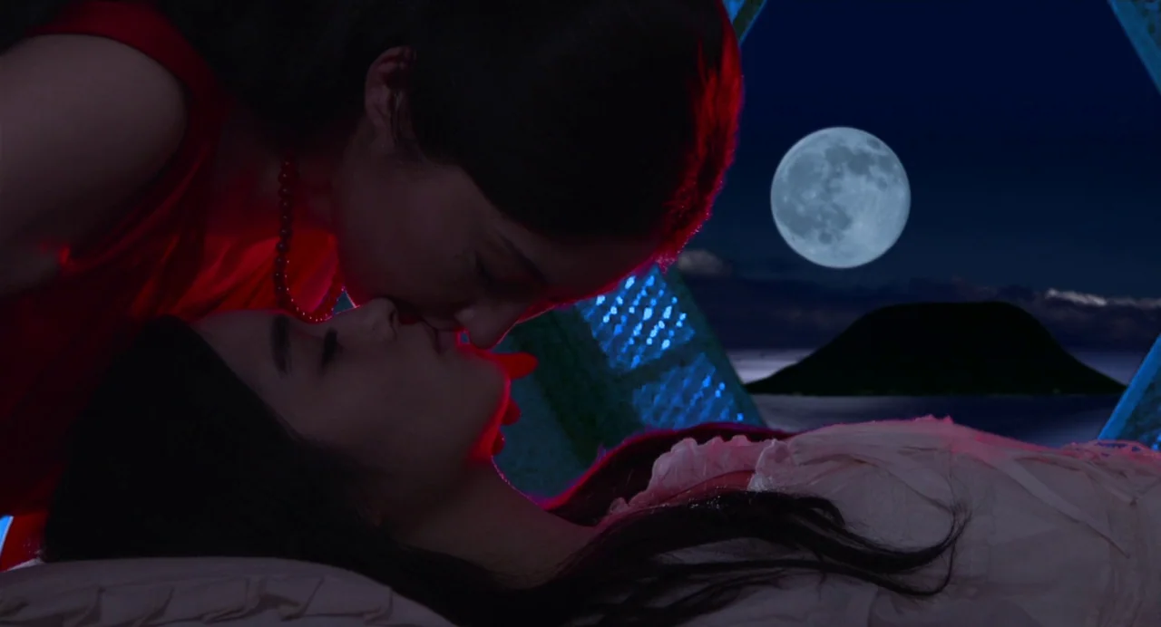 Hanagatami movie still: closeup — An interior bedroom with a large window overlooking a moonlit sea and distant hill. One woman leans over a…