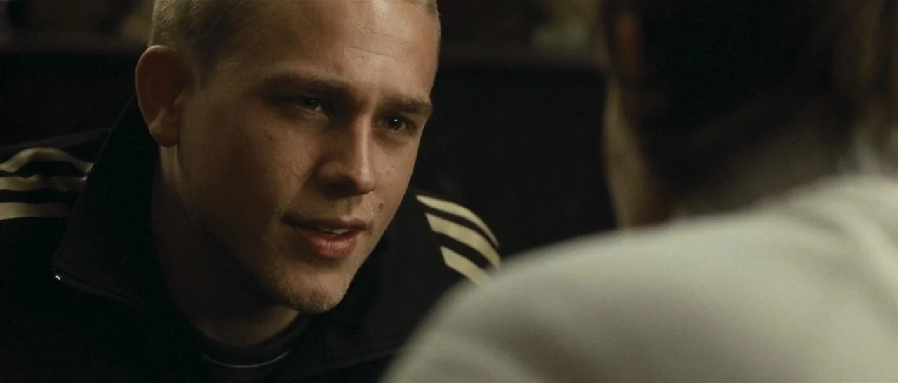 Green Street (2005) movie still: closeup — A man looks across a room toward an unseen person in the foreground. He wears a dark track jacket while…