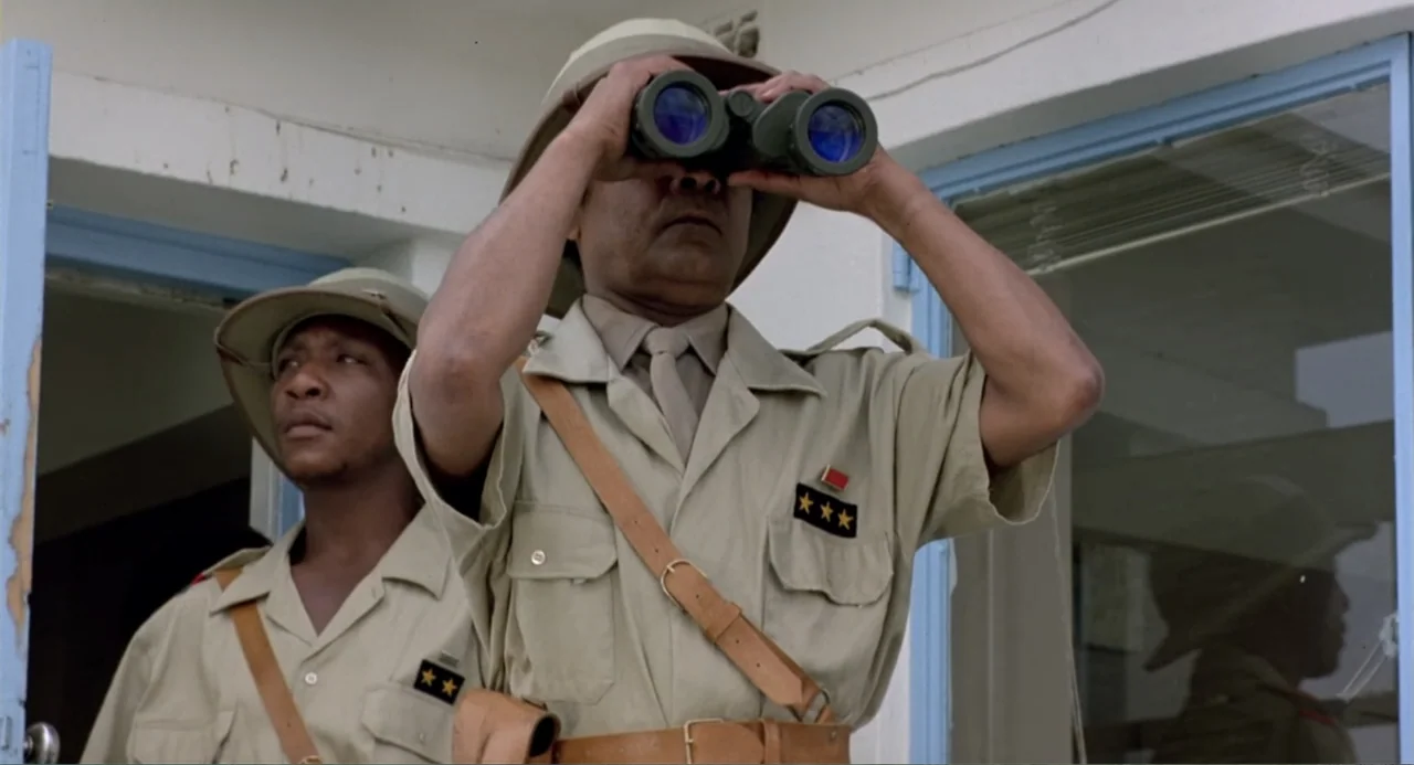 American Ninja 2: The Confrontation (1987) movie still: medium — Two men in khaki military uniforms stand in front of a white building entrance.…