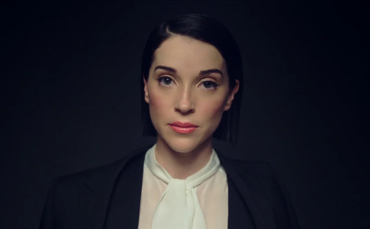 The Nowhere Inn (2020) movie still: medium — A woman stands centered against a completely black background with no visible environmental features.…