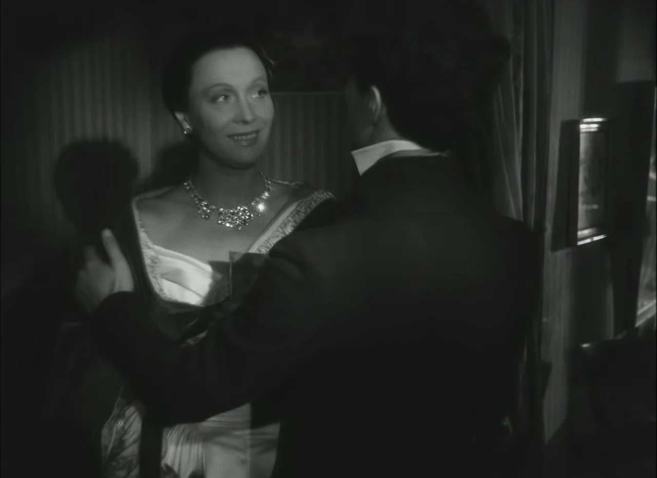 Les Enfants Du Paradis (1945) movie still: medium — A dimly lit room with striped wallpaper and a framed picture hanging on the wall. A man in a…