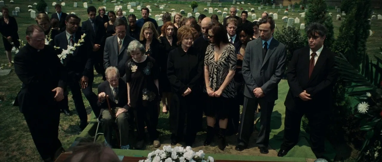 Synecdoche, New York (2008) movie still: wide — A group of people dressed in formal dark clothing stand in a green cemetery. They are gathered…