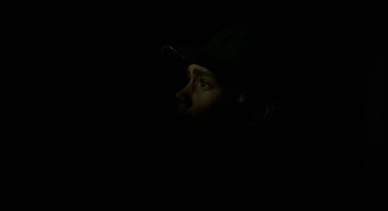 Lean on Pete (2017) movie still: closeup — A person is situated in near total darkness. Only the facial features of the individual are illuminated…