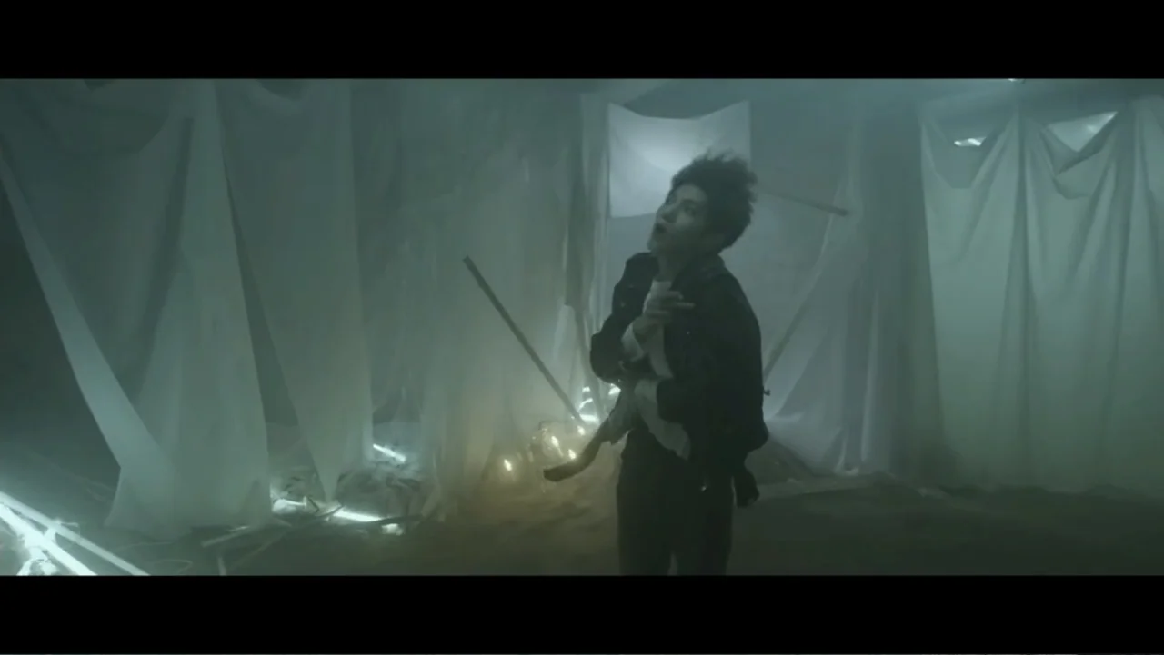 Lee Soo Man: King of K-Pop (2025) movie still: medium — A studio interior is draped in white translucent fabric hung from the ceiling. A man in a…