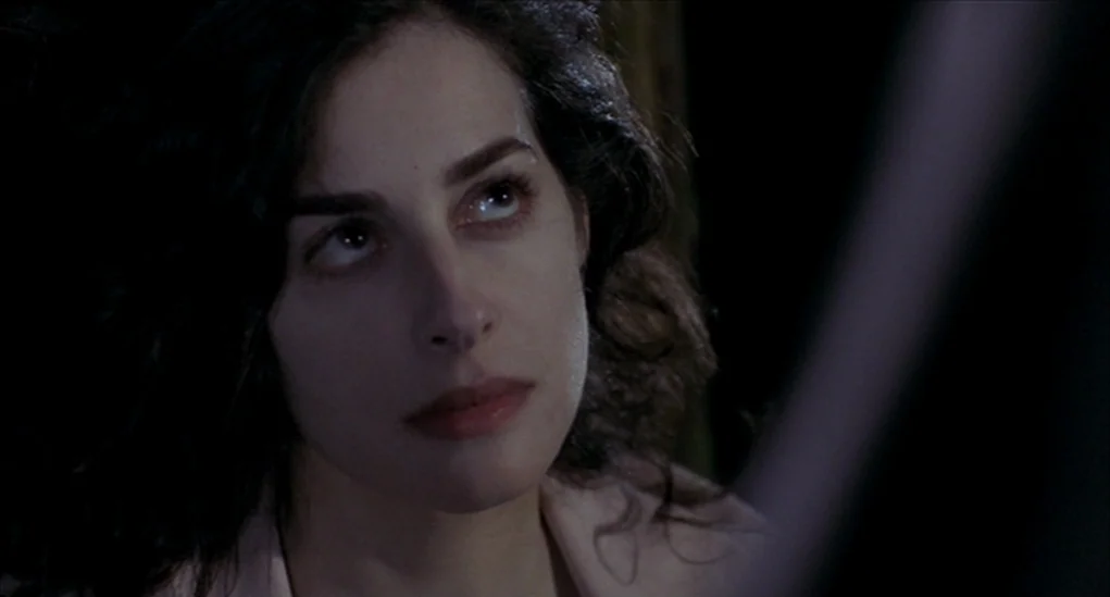 Anatomy of Hell (2004) movie still: closeup — A dark indoor setting provides a void-like backdrop for the subject. A young woman with dark hair…