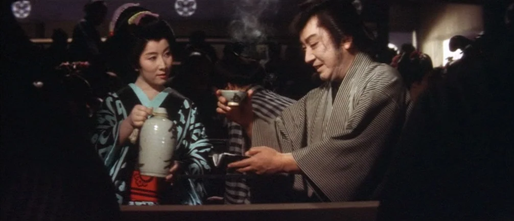 An Actor’s Revenge (1963) movie still: medium — A dimly lit indoor space featuring traditional Japanese restaurant elements in the shadows. A woman…