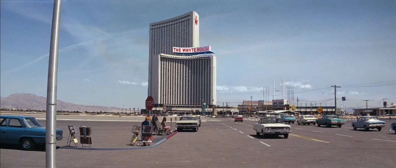 Diamonds Are Forever (1971) movie still: establishing — A vast, paved parking lot stretches toward a massive high-rise hotel building in Nevada.…