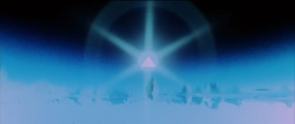 Demon Seed (1977) movie still: establishing — A bright, six-pointed light source dominates a dark, hazy, and featureless landscape. A small pink…