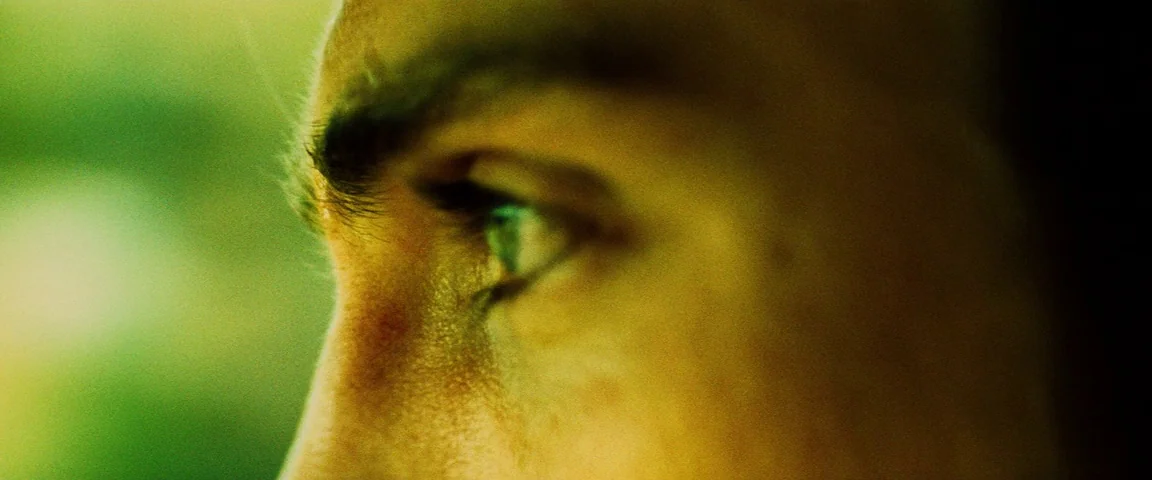 Savages (2012) movie still: closeup — A close-up view focuses on the side profile of a man's face. The subject gazes intently off-screen while the…