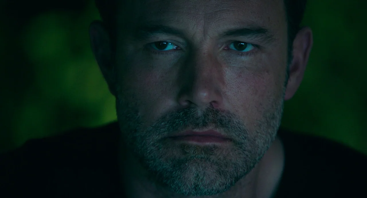 Deep Water (2022) movie still: closeup — A man's face is lit from below by a green-toned screen. The background is completely obscured in darkness.