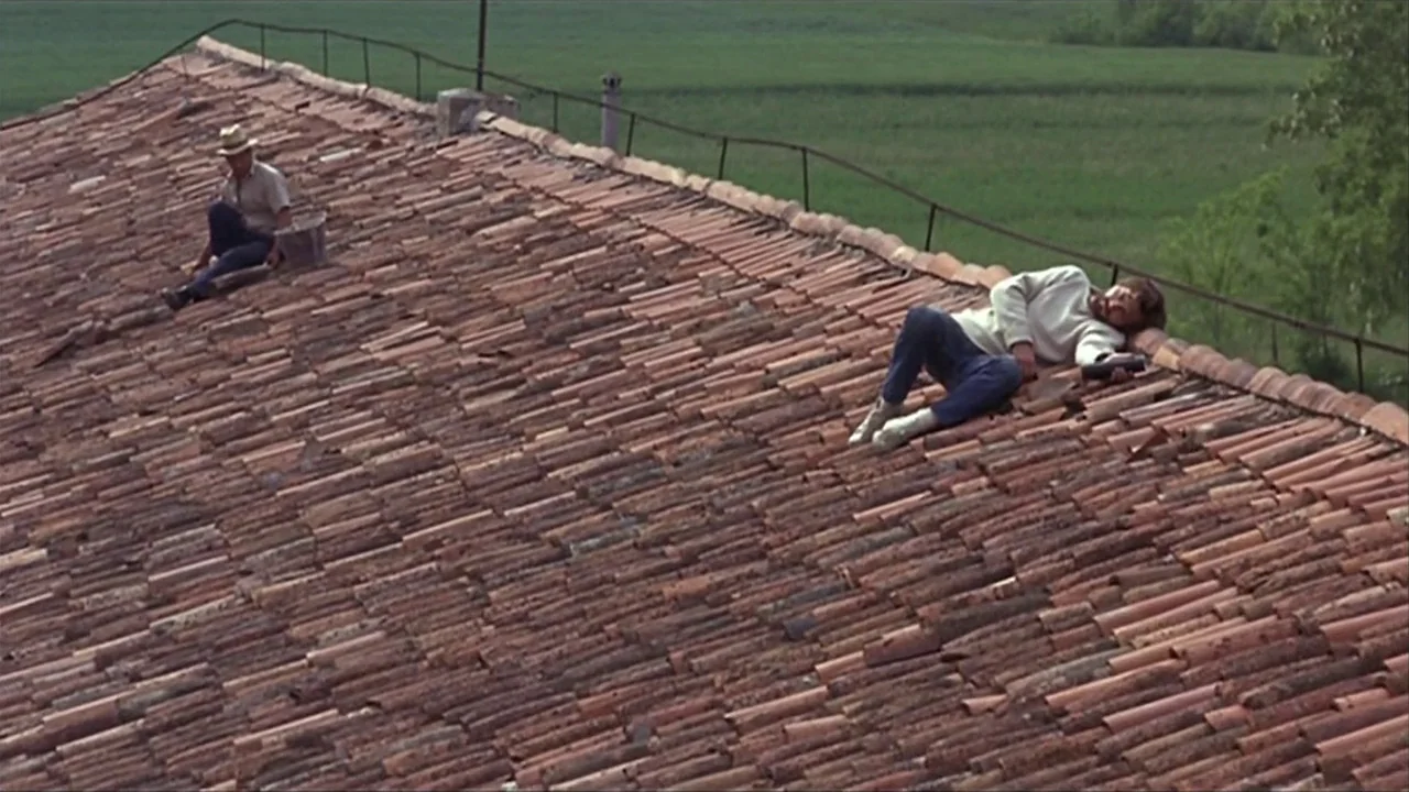A Quiet Place In The Country (1968) movie still: wide — An angled terracotta tile roof stretches across the foreground of a rural landscape. Two men…