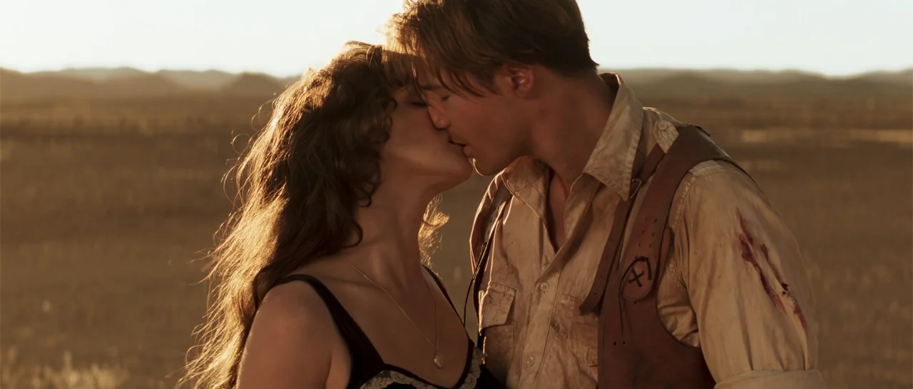 The Mummy (1999) movie still: medium — A man and woman stand in an open, dry desert landscape during golden hour. They are face-to-face in a close…