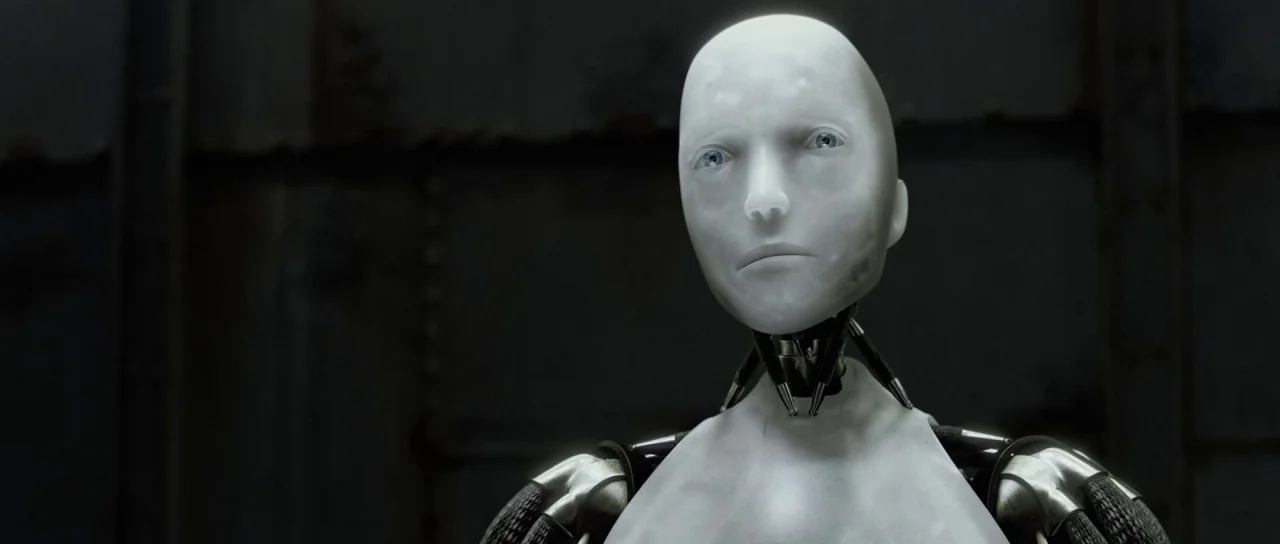 I, Robot (2004) movie still: medium — A dark industrial space features wall panels with visible rivets and metal seams. A smooth, pale humanoid…