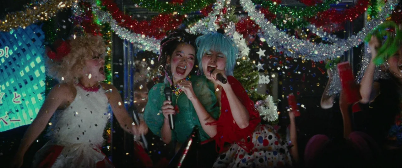 The World of Kanako (2014) movie still: medium — A festive karaoke room decorated with tinsel and Christmas greenery is filled with falling…