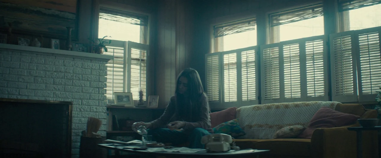 Extremely Wicked, Shockingly Evil and Vile (2019) movie still: medium — A 1970s style space with wood-paneled walls and a brick fireplace. A woman…