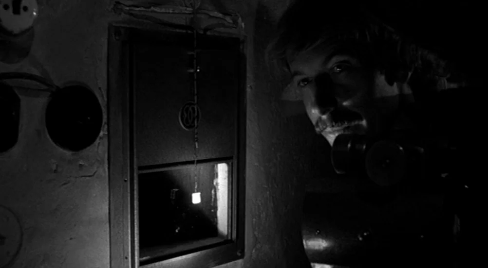 Kings of the Road (Im Lauf der Zeit) (1976) movie still: closeup — A dimly lit utility room features a small, framed aperture in a stone wall. A man…