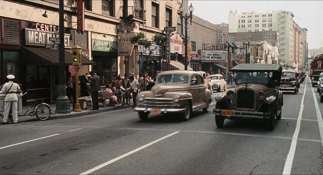 Devil In A Blue Dress (1995) movie still: wide — A bustling 1940s city street is lined with storefronts and historic commercial architecture.…