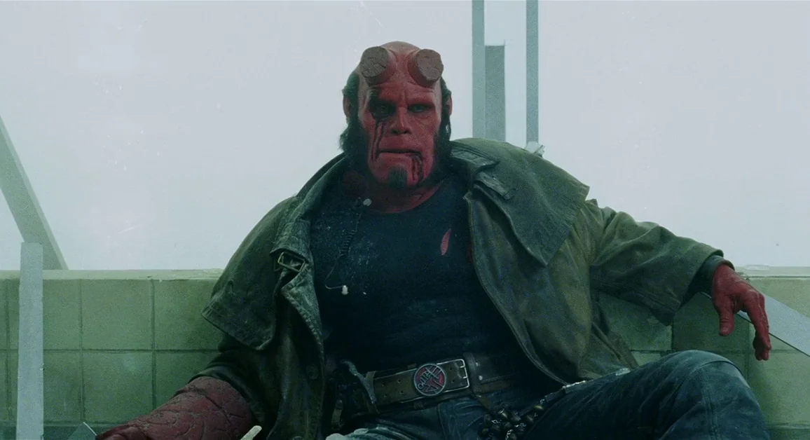 Hellboy (2004) movie still: medium — A rooftop with industrial tiled walls covered in a dense layer of grey fog. The red-skinned humanoid character…