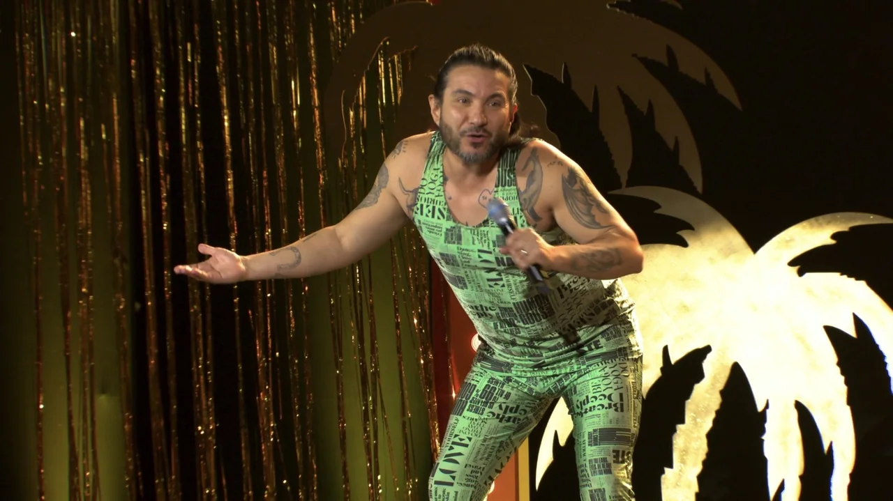 Felipe Avello: Doglover (2024) movie still: medium — A dark performance space features metallic gold fringe curtains and a black palm tree cutout. A…