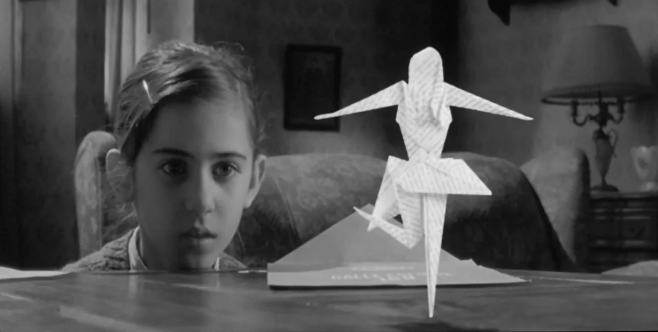 The Aerial (2007) movie still: medium — A 1940s study featuring a table with vintage desk items and patterned wallpaper. A young girl stares at a…