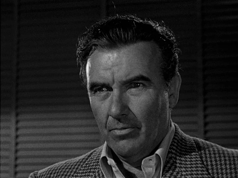 The Big Night (1951) movie still: closeup — A man is positioned in front of venetian blinds in a dimly lit room. He stares forward while the…