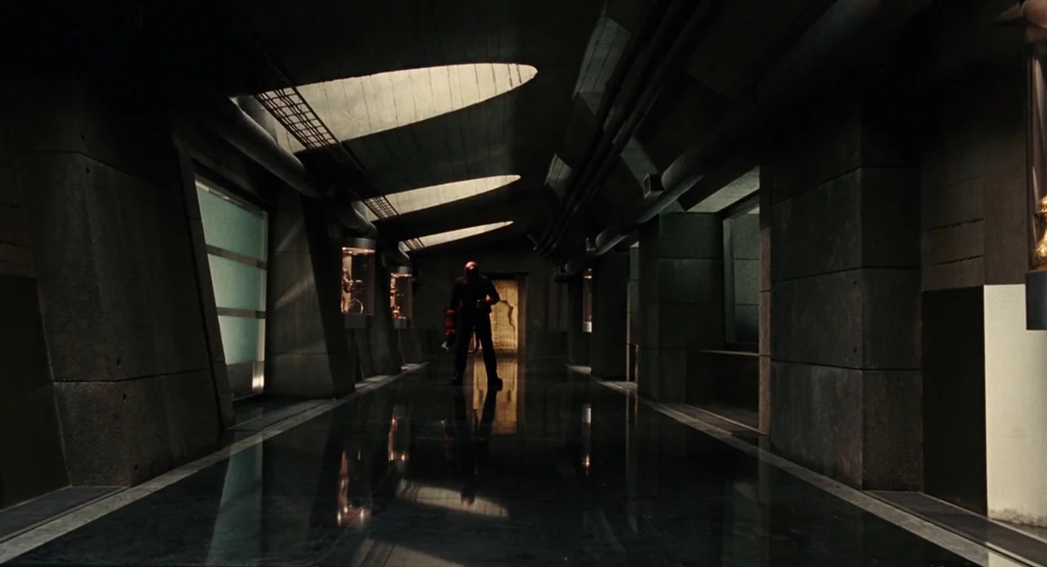 Hellboy II: The Golden Army (2008) movie still: wide — A long, dark concrete hallway features recessed ceiling lights and reflective polished…