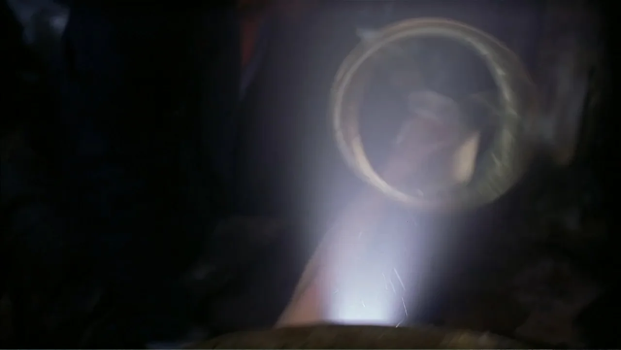 Ghost Ship (2002) movie still: closeup — A close-up view shows the illuminated interior of a dark metallic pipe. A concentrated flashlight beam…