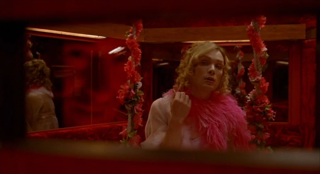 Breakfast On Pluto (2005) movie still: medium — A confined space lined with red fabric and mirrors framed by artificial floral vines. A person with…