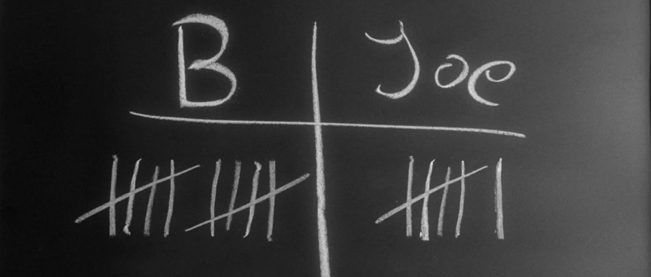 Nymphomaniac Vol 1 (2013) movie still: closeup — A dark blackboard features white chalk writing divided into two columns by lines. The names B and…