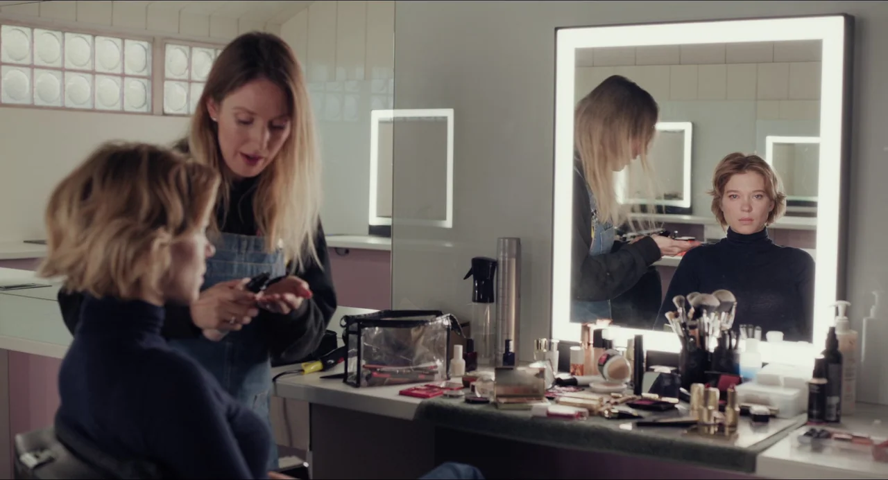 Transformers: Rise of the Beasts (2023) movie still: medium — A brightly lit makeup room with a large mirror surrounded by LED lights. A…