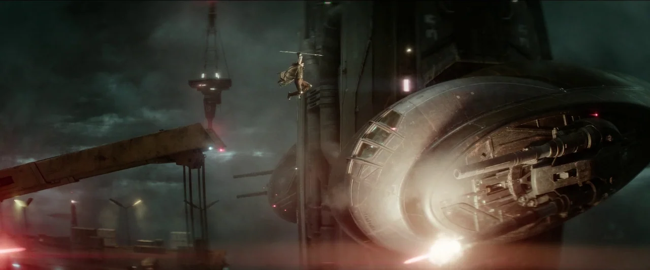 Rebel Moon – Part One: A Child of Fire (2023) movie still: wide — A dark, industrial landing platform at night features massive, sleek metallic…
