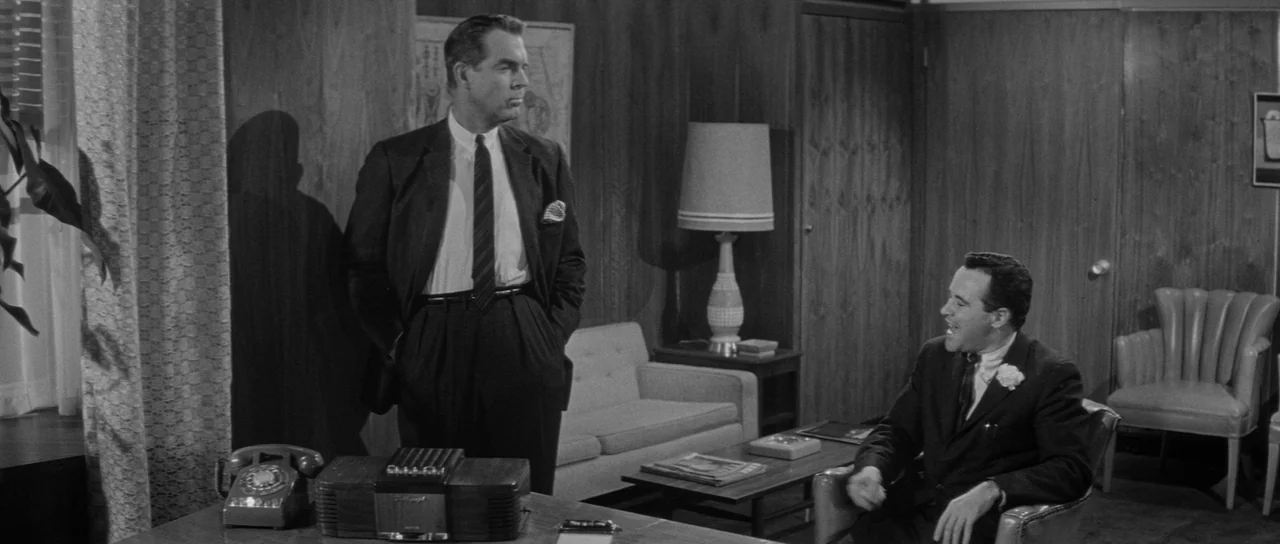 The Apartment (1960) movie still: medium — A 1950s office with wood-paneled walls features mid-century furniture and a desk in foreground. A…