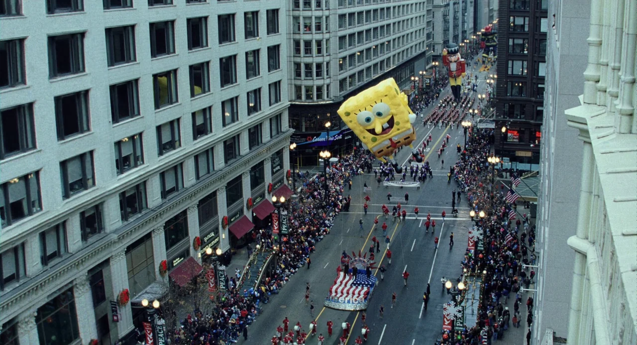 The Weather Man (2005) movie still: establishing — A high-angle view of a city street during a holiday parade. Large inflatable balloons float above…
