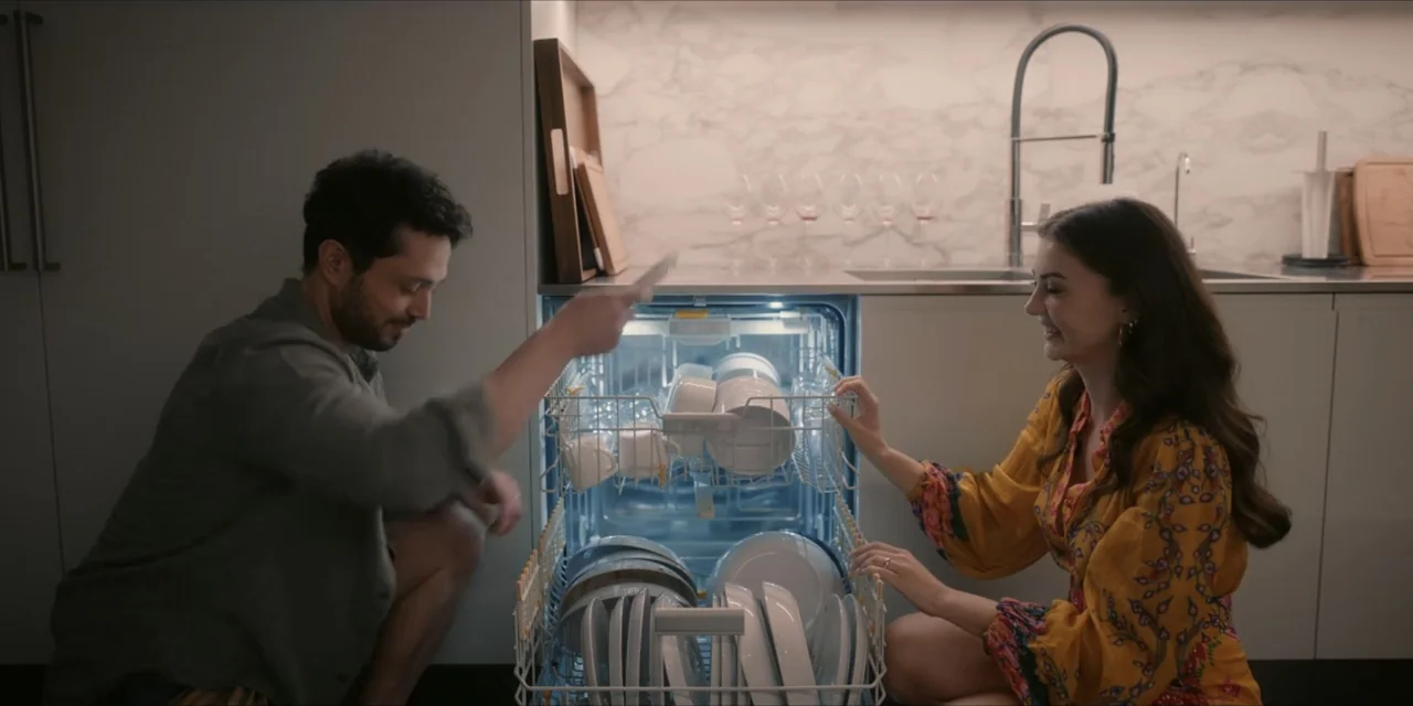 Kill Me If You Dare (2019) movie still: medium — A modern kitchen features marble wall tiling and clean white cabinetry with minimalist hardware. A…
