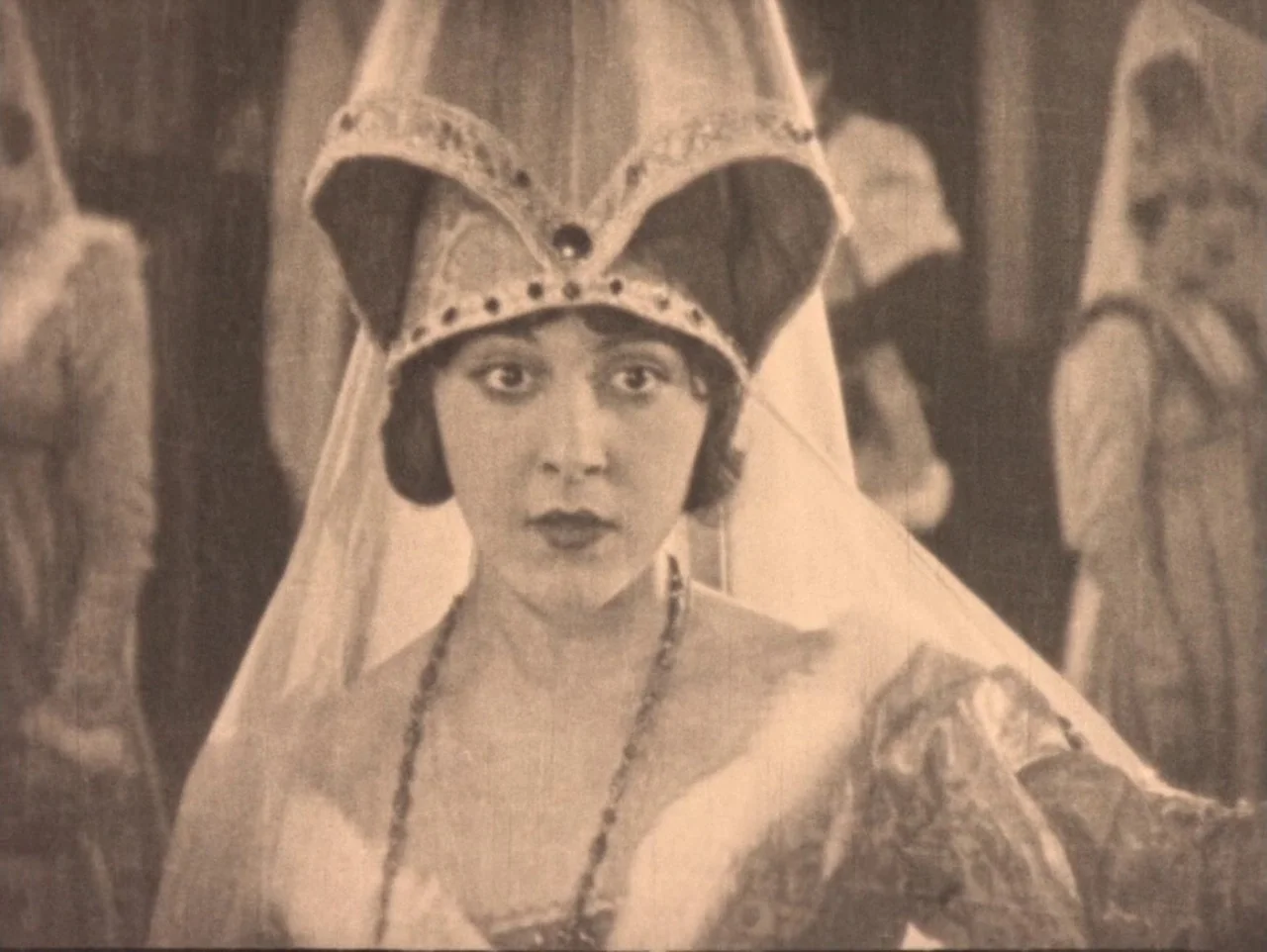 The Hunchback of Notre Dame (1923) movie still: medium — An interior space displays figures wearing historical headgear against a blurred,…